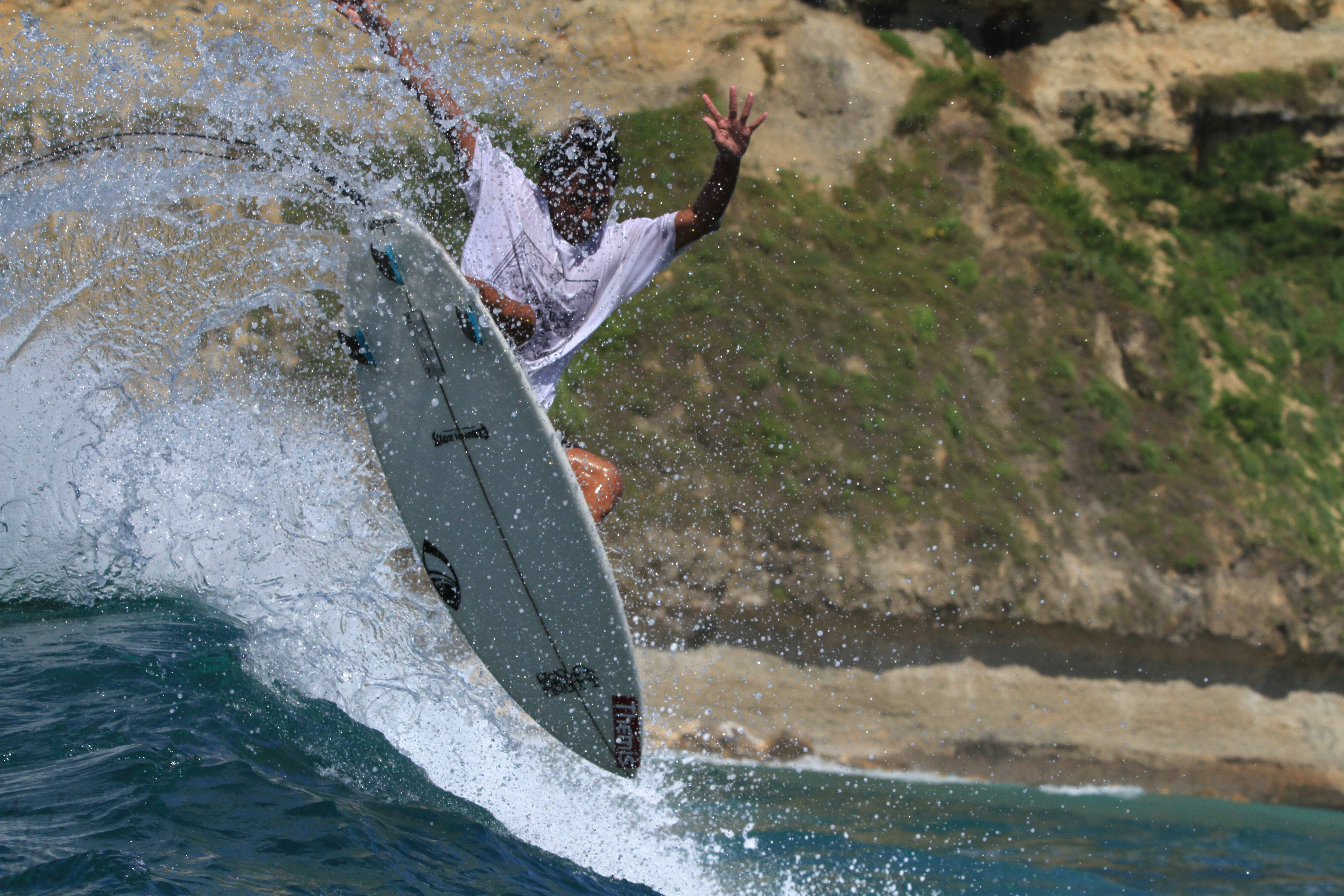 Surfer hitting the lip against the Gerupuk cliffs