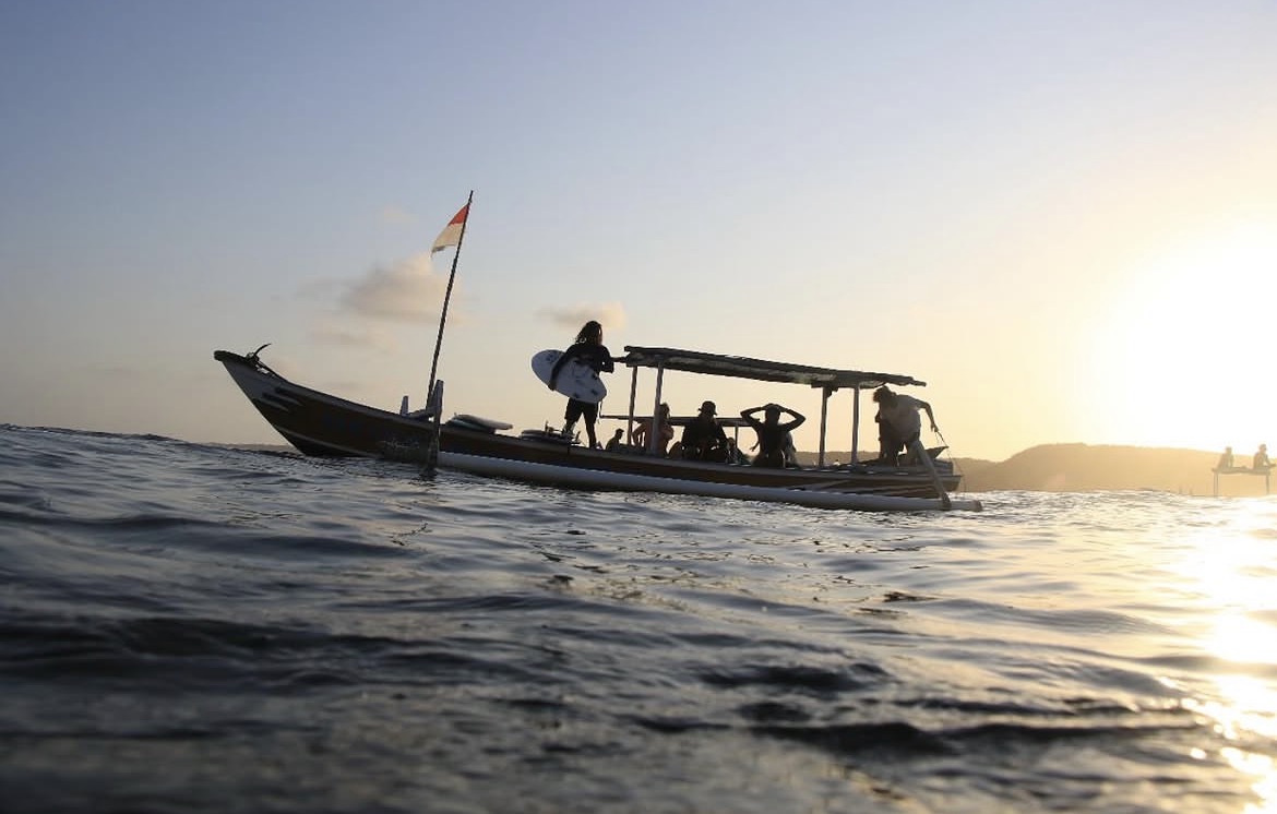 Sunset over Gerupuk Bay, Lombok — surfers heading out